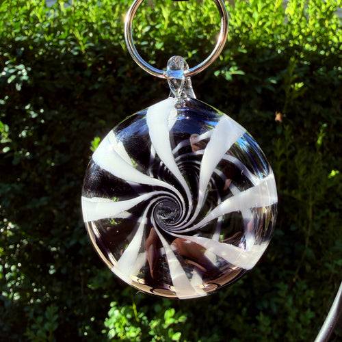 Black and white Hypnotic Cosmos glass ornament, shown as an example of the handmade swirl style. Choose two colors for your custom order.