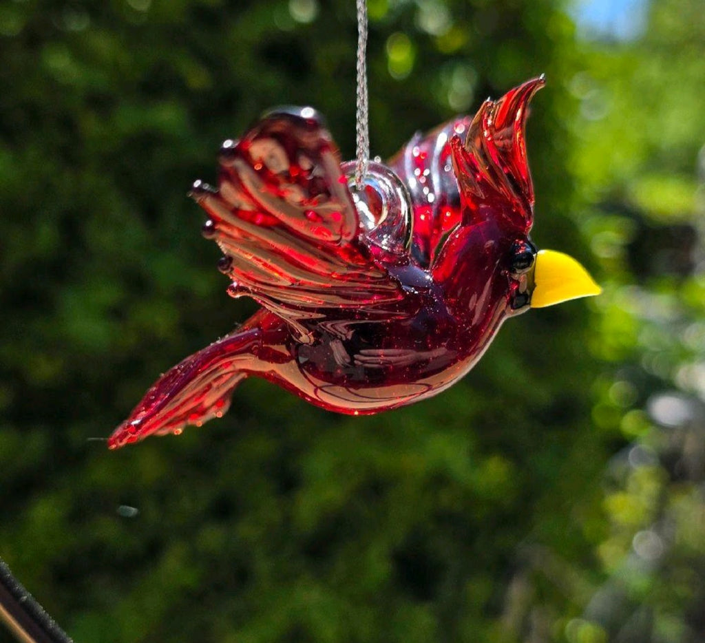 Handmade ruby-red glass cardinal ornament with raised wings, a tall crest and yellow beak